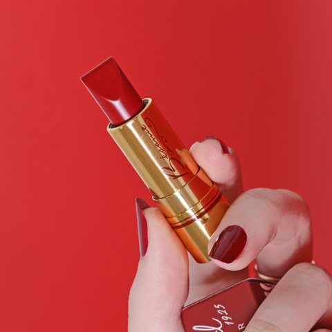 Hand holding Bésame Cosmetics red lipstick